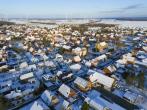 Snow-covered village with a church and a series of wind turbines on the horizon on a clear winter