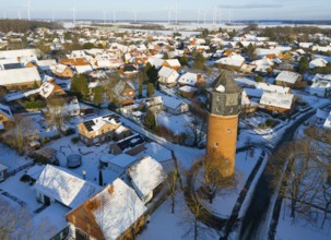 Winter village view with a distinctive water tower surrounded by snow-covered houses and distant