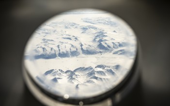 View from an airplane window of snowy arctic mountain landscape with glaciers, aerial view,