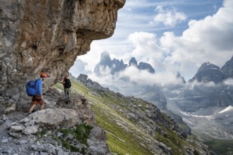 Two mountaineers on a path in front of a picturesque mountain landscape with rocky peaks, Via