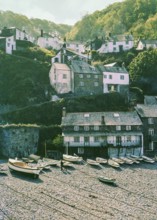 Historic buildings in harbour boats on beach at Clovelly, north Devon, England, UK 1960s