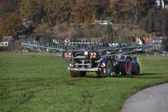 Farmer with a tow hose fertilizer in a meadow, Eschenbach, Middle Franconia, Bavaria, Germany