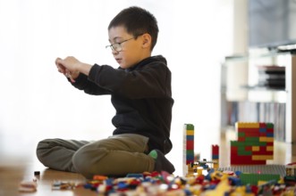 Boy, 6 years, glasses, multi-ethnic, plays with Lego, concentrates, constructs, builds, Stuttgart,