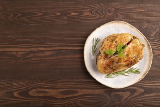 Fried Turkey Thigh with spices and rosemary on plate on brown wooden background. top view, flat