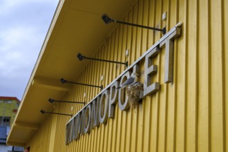 Yellow building of the Norwegian state wine monopoly with sign and floodlights and a breeding