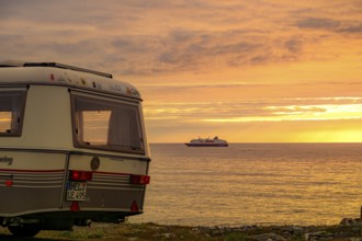 Eriba Touring Troll caravan by the sea, sunset and a Hurtigroute ship on the horizon on the Barents