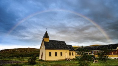 Nordford chapel on Ytre Syltefjord under a rainbow surrounded by cloudy sky, small church with