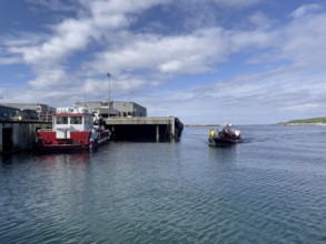 Port of the town of Vardö with the harbour master's ship and the incoming a running rigid dinghy