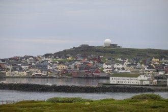 View of the port city of Vardø with large NATO radar systems on a hill in the background, Vardö,