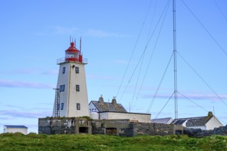 White lighthouse with red tip and antennas on the bird island of Hornoya, surrounded by grassy