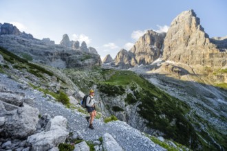 Female mountaineer hiking on a hiking trail in front of picturesque mountain scenery in the