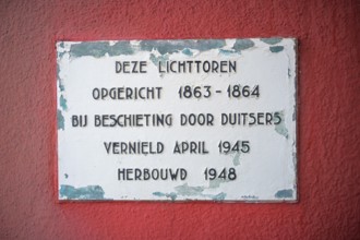 Memorial plaque on a red wall with text about the lighthouse de Cocksdorp and historical events of