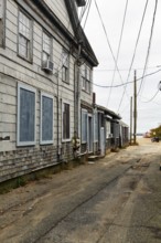 Alley leading to the ocean, weathered timber houses, traditional wood paneling, power lines, former