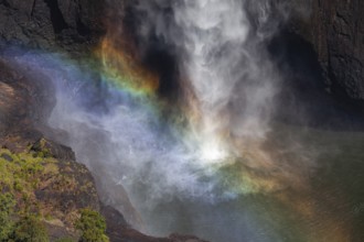 Daytime top view at Wallaman Falls with rainbow in mist over cascading water, Queensland, Australia