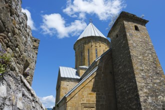Medieval church building with a high tower and a blue sky in the background, Ananuri Castle,