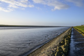 Wide view of quiet North Sea landscape with dike and water horizon, An extensive coastal landscape