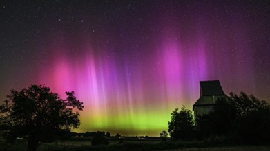 Colourful aurora above the EXPO observatory in magenta and shades of green in front of a starry