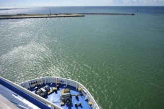 Front view of a TT-Line ferry leaving the port exit under a blue sky with a clear horizon,