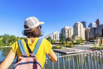 Tourist with a backpack is enjoying the cityscape of calgary, alberta, from a bridge, taking in the