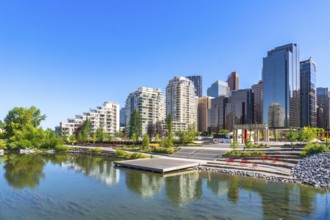 Modern buildings of downtown calgary reflecting in the calm water of a pond in st. Patrick's island