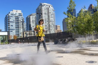 Female tourist walking in a foggy square in calgary city center during a sunny summer day, enjoying