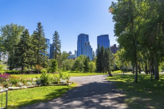 Lush green trees and flowerbeds in central memorial park provide a vibrant foreground to the modern