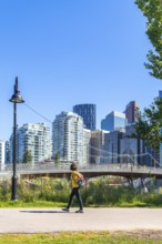 Young woman tourist walking in a city park in calgary, canada, enjoying the summer weather and