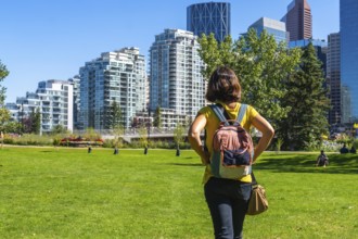 Female tourist with a backpack enjoying a sunny day in calgary's park, taking in the stunning views
