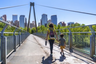 Mother and child are enjoying a leisurely stroll across a pedestrian bridge, set against the
