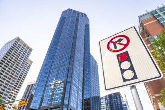 Low angle view of a no right turn sign and traffic light against towering modern skyscrapers in