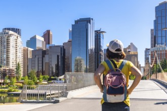 Young woman tourist with backpack admiring the modern skyline of calgary, alberta, canada, on a