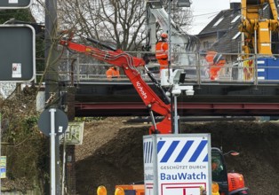 Construction workers with construction machinery on a railway bridge construction site,