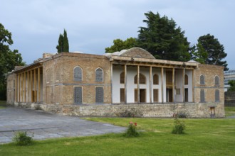 Old building with impressive brick walls and elegant columned entrance in garden surroundings,