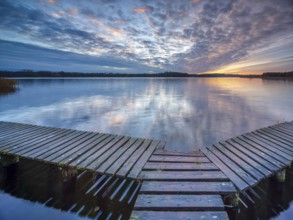 Evening at Schaalsee, wooden walkway with beautiful clouds in the sky at sunset, Schaalsee