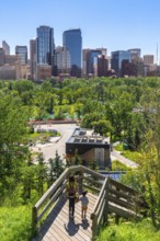 Mother and son descending wooden stairs, enjoying the vibrant urban park with the stunning calgary