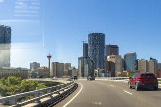 Cars driving along a highway showcase the vibrant calgary skyline, featuring the iconic calgary