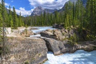 Turquoise bow river flowing beneath a natural bridge rock formation, framed by cascade mountain,