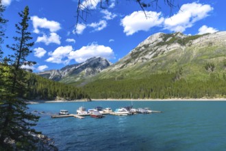 Many motorboats are resting on the turquoise waters of lake minnewanka, surrounded by the imposing