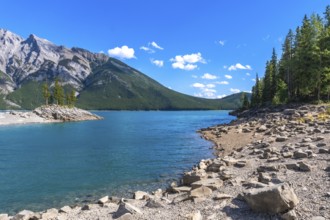 Breathtaking turquoise water of lake minnewanka reflecting the majestic canadian rockies under a