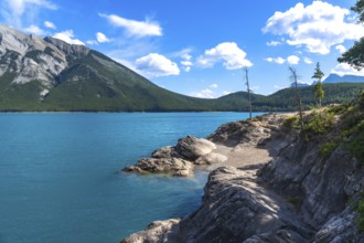 Breathtaking turquoise waters of lake minnewanka reflecting the majestic canadian rockies under a