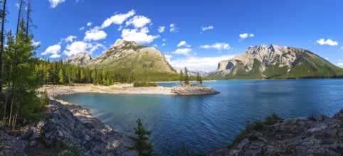 Sunlight illuminating the turquoise waters of lake minnewanka, reflecting surrounding mountains and