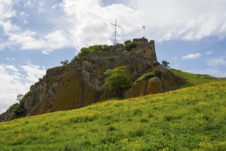 An old castle on a green hill under cloudy sky with a cross on top, Kveshi fortress, Bolnisi,