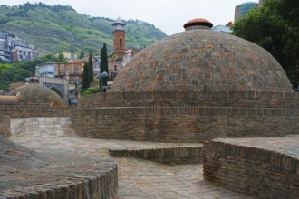 Traditional domes and brick buildings nestled in mountainous landscape, sulfur baths, Abanotubani