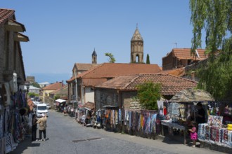 A lively market street in a village with people buying souvenirs at colorful stalls, Old Town,