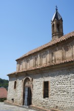 Stone church with red tile roof and bell tower in sunny weather, Church of St. George, Old Town,