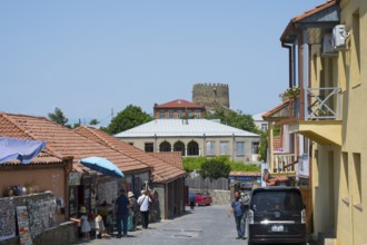 Urban street scene with people, red roofs and castle in the background, old town, Sighnaghi,