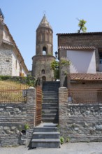 Old stone tower with adjacent building and stone stairs, sunny weather, St. George Church, Old