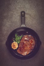 Grilled rib eye steak, in a cast-iron skillet, top view, homemade, no people