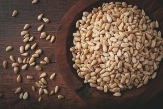Peeled pine nuts, in a wooden bowl, on a wooden table, close-up, no people
