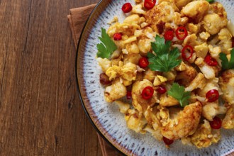 Spicy fried cauliflower served on a wooden countertop
